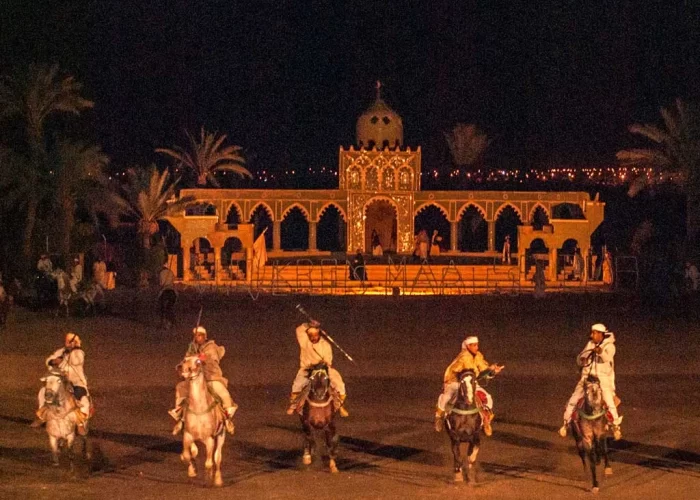 An electrifying performance at the Dinner Show Fantasia at Chez Ali Restaurant Marrakech with Moroccan horsemen in traditional attire exhibiting their skills, under a starry night sky