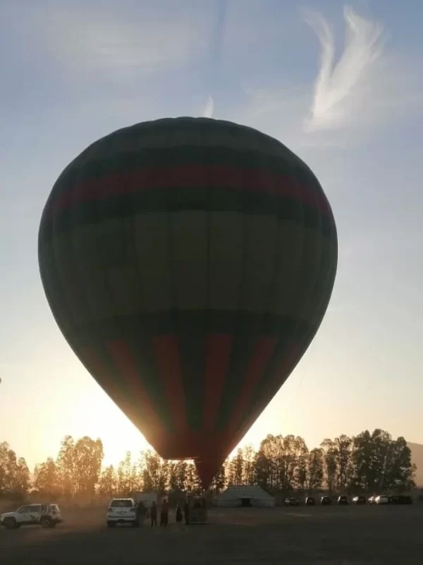 Colorful hot air balloon majestically floating over the mesmerizing landscape of Marrakech during a half-day hot air balloon flight, offering a bird's-eye view of the city and its surrounding countryside