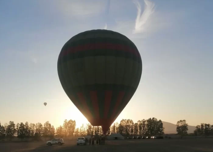 Colorful hot air balloon majestically floating over the mesmerizing landscape of Marrakech during a half-day hot air balloon flight, offering a bird's-eye view of the city and its surrounding countryside