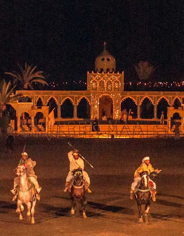 A vibrant and bustling dining scene at Restaurant Chez Ali in Marrakech, showcasing traditional Moroccan décor and a captivating Fantasia performance under the starlit sky.