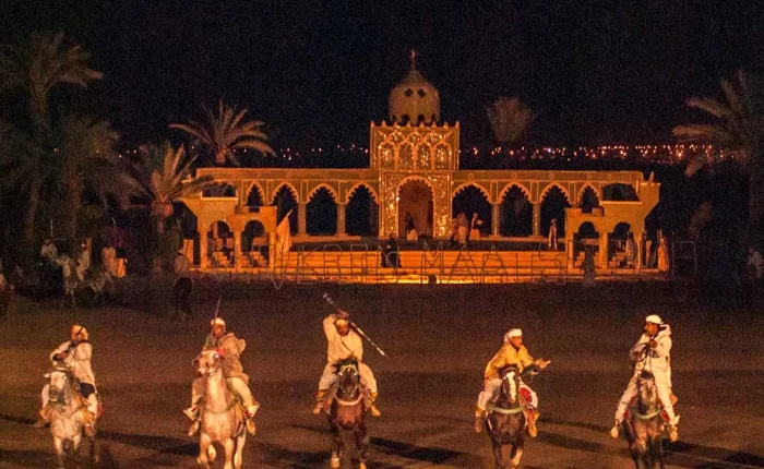 A vibrant and bustling dining scene at Restaurant Chez Ali in Marrakech, showcasing traditional Moroccan décor and a captivating Fantasia performance under the starlit sky.